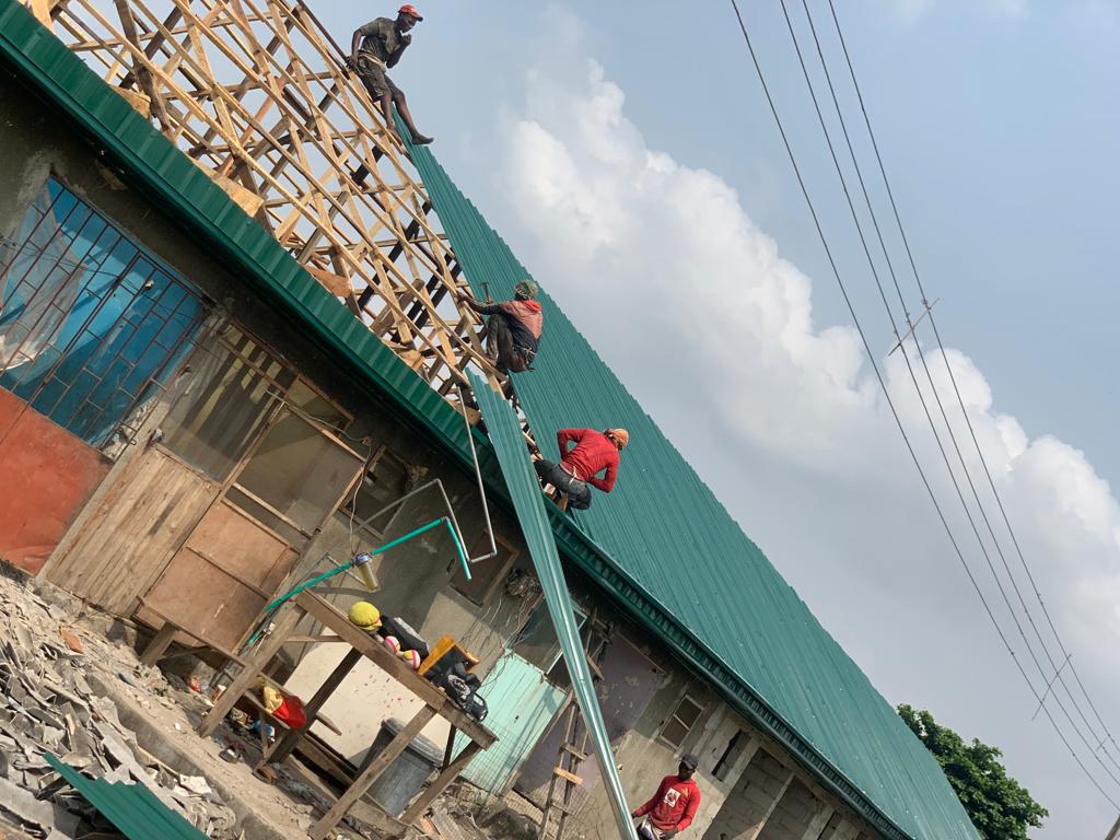 Roofing team installing green long-span aluminium sheets on timber trusses
